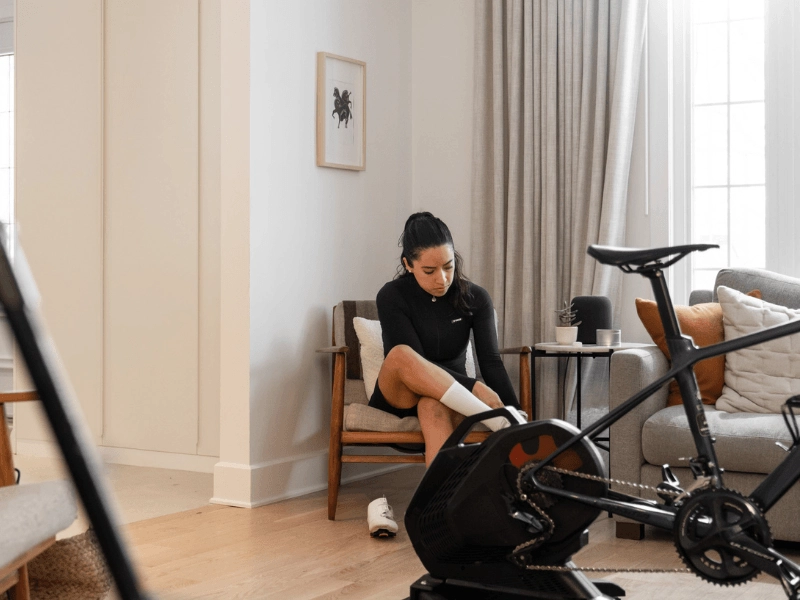 Cycling Related Foot Pain - MyVeloFit Woman with foot pain from cycling sitting in a Livingroom