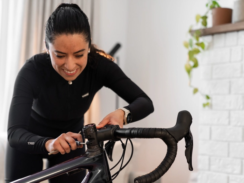 Woman adjusting bicycle handlebars for better riding indoors.